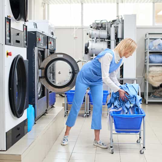 Wäscherei, Frau belädt Waschmaschine